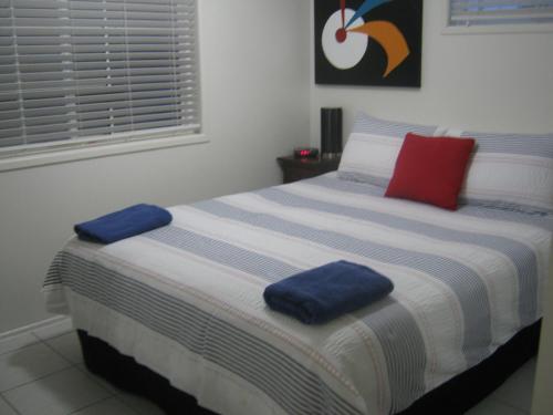 a bedroom with a bed with blue and red pillows on it at Campwin Beach House in Sarina