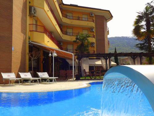 a swimming pool with a fountain in front of a building at Hotel Imperial ***S in Garda