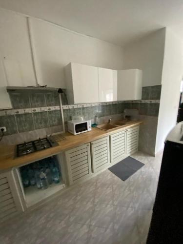 a kitchen with white cabinets and a counter with a microwave at Mo'Passa Suite in Mamoudzou