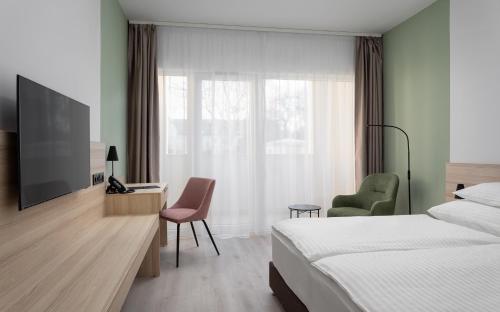 a hotel room with a bed and a desk and a television at Hunguest Hotel Flóra in Eger