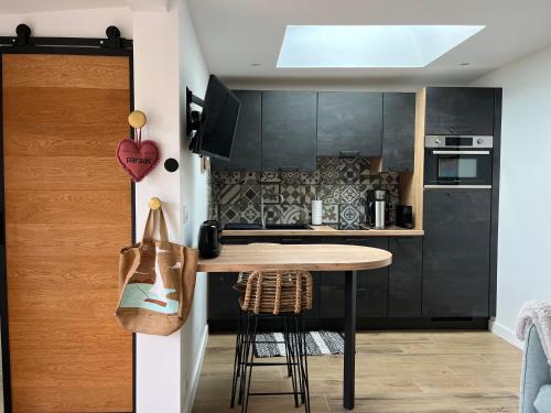 une cuisine avec des armoires noires et une table en bois dans l'établissement Lodge LE CABANON accès direct plage !, à La Turballe