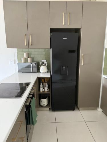 a kitchen with a black refrigerator and white cabinets at Vijas Haven in Windhoek