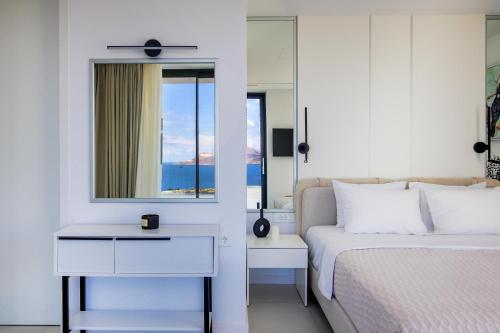Un dormitorio blanco con una cama y un espejo. en Villa OMORFI, en Kókkinon Khoríon