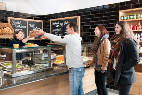 a group of people standing around a counter in a bakery at Hotel zur Post in Rohrdorf