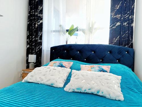 a blue bed with two pillows on it at A&R Apartamenty Wenedów III, bezpłatny prywatny parking in Koszalin