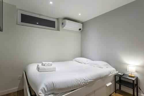 Cette chambre blanche dispose d'un lit et d'une télévision murale. dans l'établissement Smartstay Louis Mille - Gratte-Ciel, à Villeurbanne