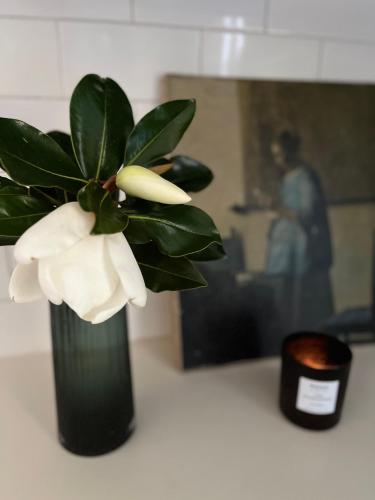 a black vase with a white flower in it at Executive Cottage, Luxe 1930s Stay in the Heart in Albury