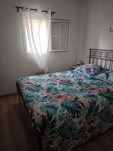 - une chambre avec un lit doté d'un couvre-lit floral et d'une fenêtre dans l'établissement Jasse 632, à Gallargues-le-Montueux