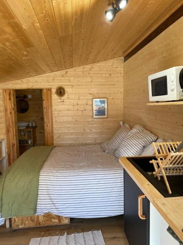 Ce lit se trouve dans une petite pièce d'une cabane en rondins. dans l'établissement cabane, à Saint-Vincent-de-Paul
