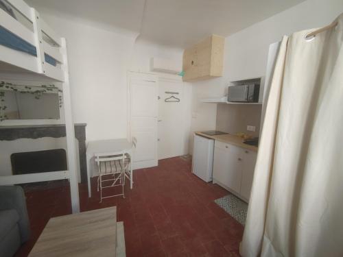 une petite cuisine avec des armoires blanches et une table dans l'établissement Studio cosy centre historique, à Arles