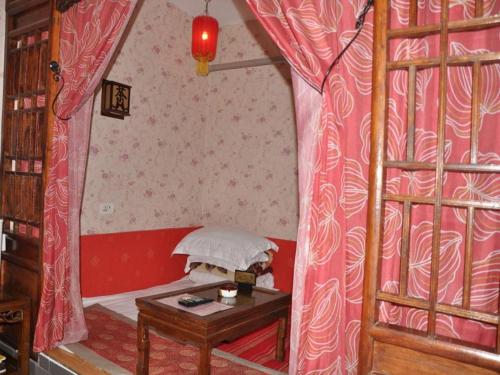a small room with a bed and a table at Pingyao Yufengheng Hotel in Pingyao