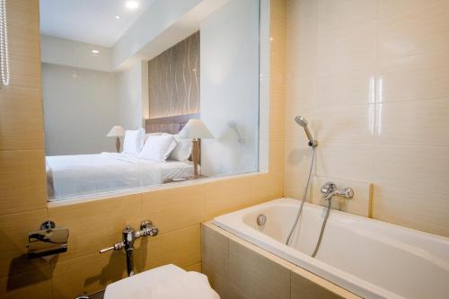 bagno con vasca, letto e specchio di Istana Nelayan Hotel & Convention Powered by Archipelago a Kerontjong Satu