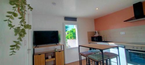 a kitchen with a television and a table and chairs at Le Ptit Kozhi, Confort, Nature & Plages in Plouay