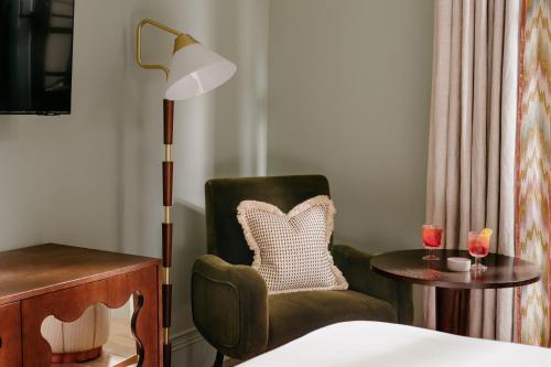 a room with a chair and a table with a lamp at The Hoxton, Florence in Florence