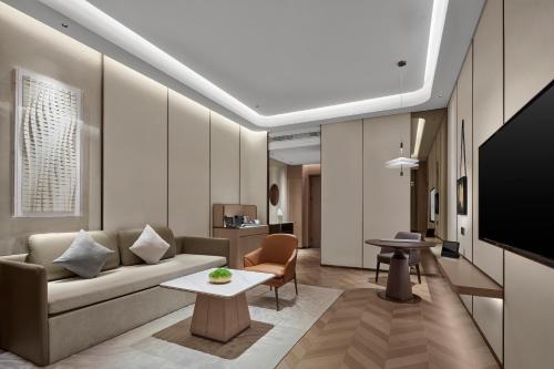 a living room with a couch and a tv at Wanda Jin Hotel Ordos in Ordos