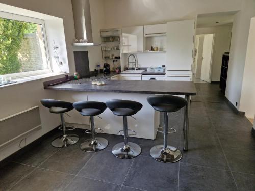 une cuisine avec un îlot avec quatre tabourets de bar dans l'établissement Gîte du moulin, à Saint-Loup-Hors