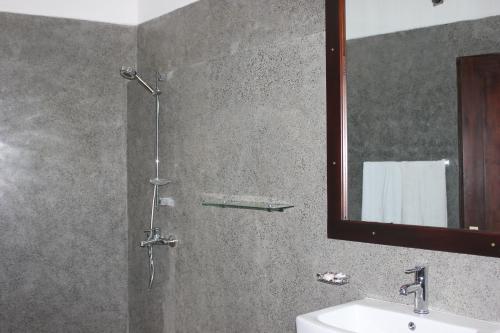 a bathroom with a shower with a sink and a mirror at Hideaway Lodge in Tangalle