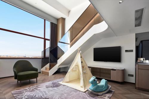 a living room with a staircase and a tv at Wanda Jin Hotel Ordos in Ordos