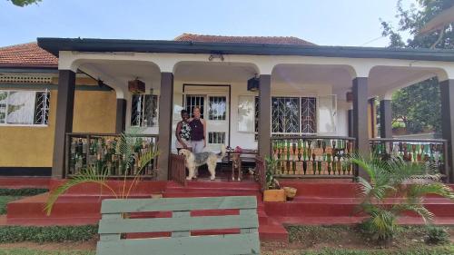 a man and a dog standing on the front of a house at Guest room 1, A home away from home in Kampala