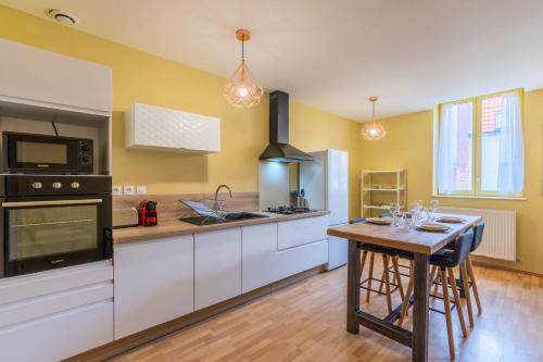 a kitchen with white cabinets and a table with chairs at Appartement 2 chambres proche metro et parking in Roubaix