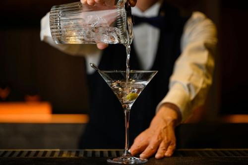 a person pouring a drink into a martini glass at Courtyard by Marriott Fukui in Fukui