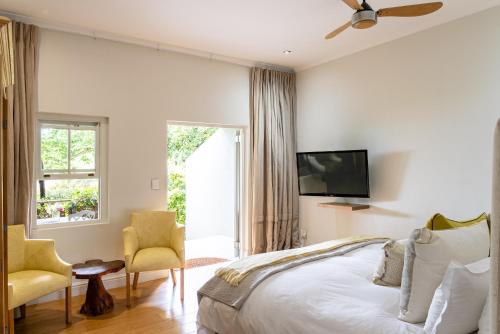 a bedroom with a bed and two chairs and a tv at Angala in Simondium