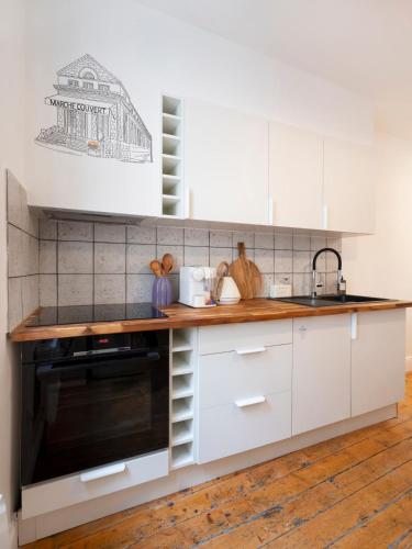 La cuisine est équipée de placards blancs et d'un four micro-ondes noir. dans l'établissement Studio Secundo, à Metz