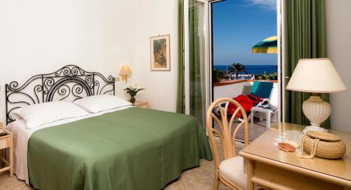 a bedroom with a green bed and a balcony at Hotel Villa Angelica in Ischia