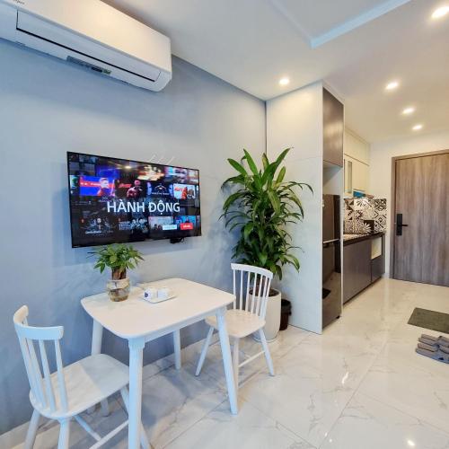 a dining room with a white table and chairs and a tv at LaHomestay Hồng Hà in Hanoi