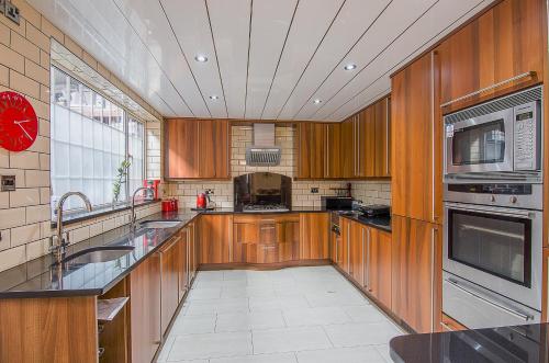 a large kitchen with wooden cabinets and stainless steel appliances at Forest Guest House in South Shields