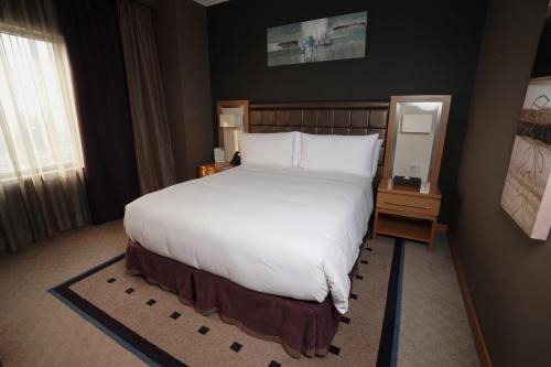 a bedroom with a large white bed and a window at Divan Erbil Hotel in Erbil