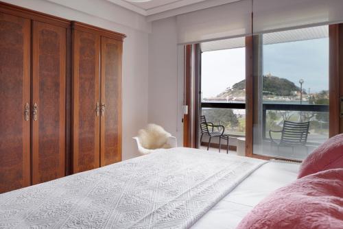 a bedroom with a bed and a large window at Palacio Miramar by FeelFree Rentals in San Sebastián