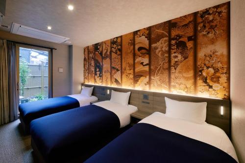3 Betten in einem Zimmer mit Gemälden an der Wand in der Unterkunft Minn Gion Kamogawa in Kyoto