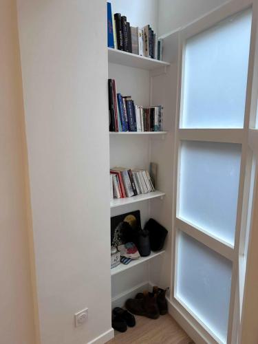 une étagère avec des livres et des chaussures dans une chambre dans l'établissement Atypical Loft in the Heart of the Marais, à Paris