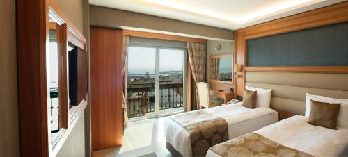 a hotel room with two beds and a large window at Ilkbal Deluxe Hotel &Spa Istanbul in Istanbul