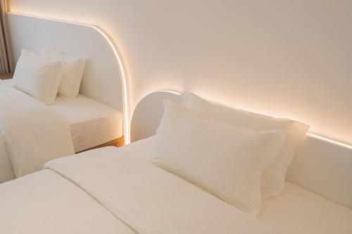 a room with two beds with white pillows and a chair at 一花一树音影民宿Tian Men mountian Branch in Wangjiazhai
