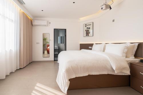 a white bedroom with a large bed with white sheets at 一花一树音影民宿Tian Men mountian Branch in Wangjiazhai