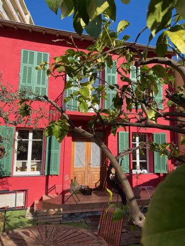 une maison rouge avec un arbre devant elle dans l'établissement Maison de ville avec jardin, à Nice