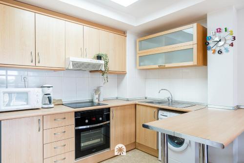 a kitchen with wooden cabinets and a sink and a microwave at Mediterranean Way - Ontario in Salou