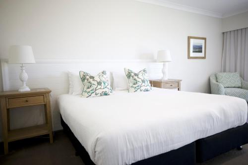 a bedroom with a large white bed and a chair at Nu Leaf Retreat in Pokolbin