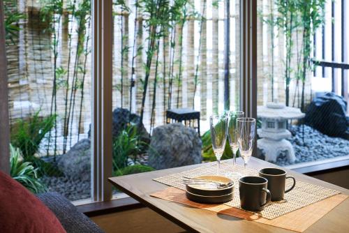 a table with cups and glasses on it with a window at Minn Gion Kamogawa in Kyoto