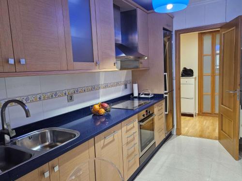 a kitchen with wooden cabinets and a sink at PISO EN EL CENTRO DE NIGRAN CERCA DE PLAYA AMERICA in Nigrán