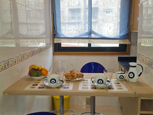 a table with cups and bowls of fruit on it at PISO EN EL CENTRO DE NIGRAN CERCA DE PLAYA AMERICA in Nigrán
