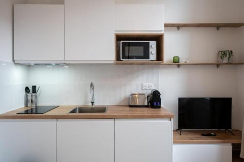 une cuisine avec un évier et un micro-ondes dans l'établissement Grand studio rénové, proche tram, à Tourcoing