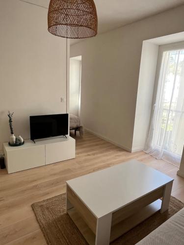 Il comprend un salon doté d'une table blanche et d'une télévision. dans l'établissement Grand studio cosy - A deux pas de la gare, à Agen