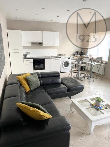 un salon avec un canapé noir et une table dans l'établissement Maison 1925, Méricourt 62, à Méricourt