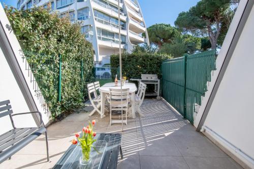 un patio avec une table et des chaises et un bâtiment dans l'établissement Les pins d'azur, à La Grande Motte