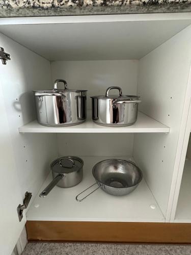 two pots and pans sitting on shelves in a kitchen at Quarto de Casal Privativo- Room 1 in Santa Cruz