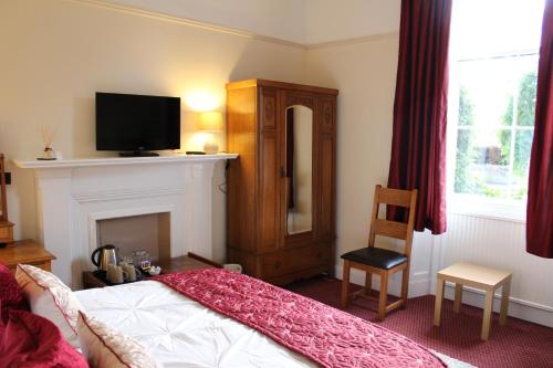 a bedroom with a bed and a television and a chair at Brackness House Luxury B&B in Anstruther