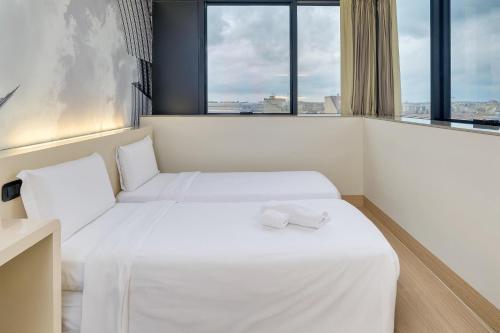 two beds in a room with two windows at B&B Hotel Milano Sesto Marelli in Sesto San Giovanni